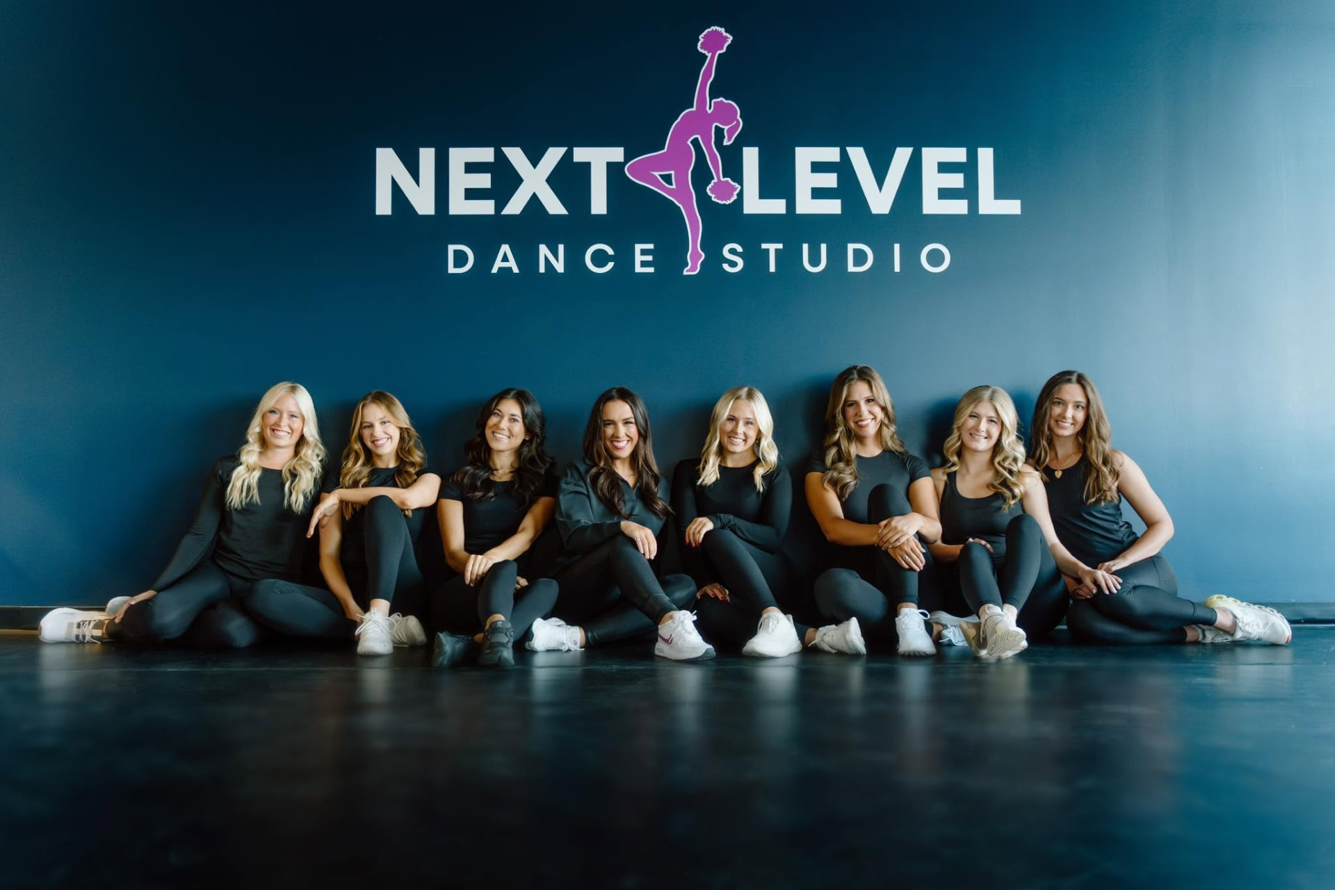Next Level Dance Studio dancers together in the studio in front of the studio logo